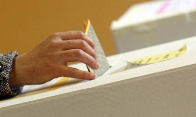 Foto di una persona che imbuca la scheda elettorale nell'urna
